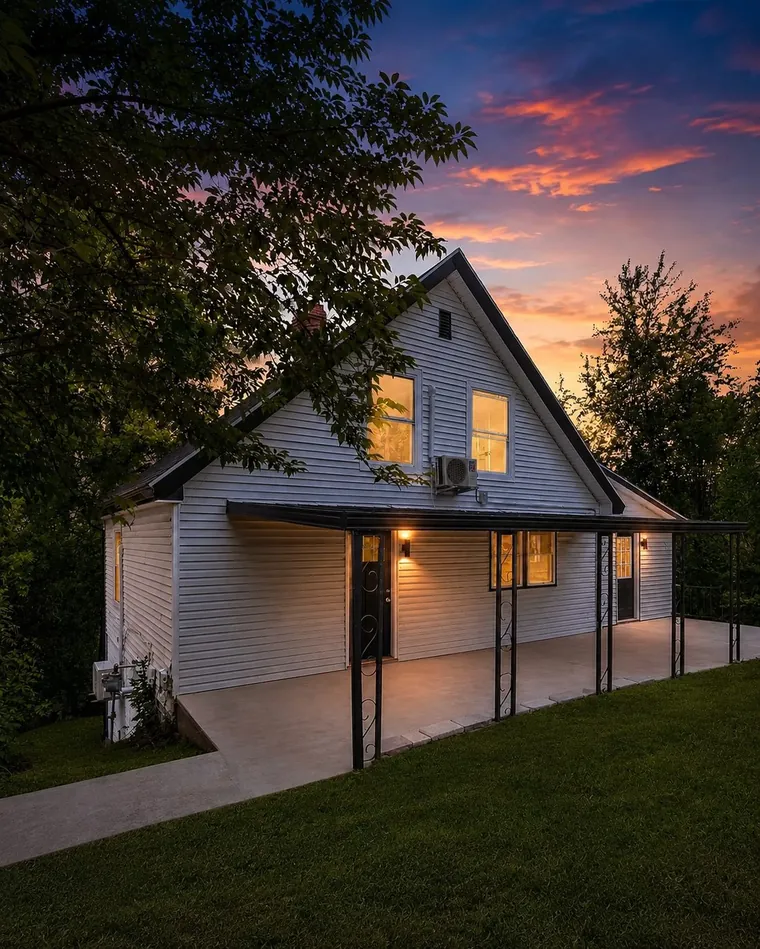 The same exterior re-rendered at twilight with warm interior lights